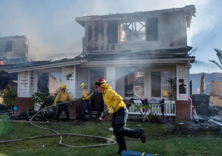 Firefighters hose down a burning house during the Tick Fire in Agua Dulce near Santa Clarita, California on October 25, 2019