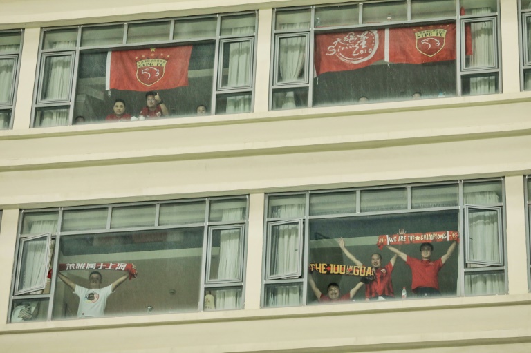 Fans cheer from a hotel beside the stadium during the Chinese Super League (CSL) football match between Shanghai SIPG and Tianjin Teda in Suzhou